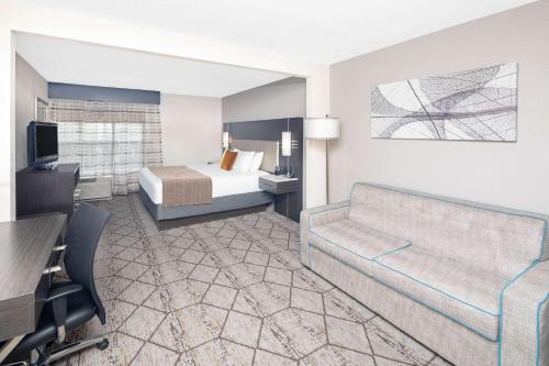 a hotel room with a bed and a couch at Wingate by Wyndham Greenville Airport in Greenville