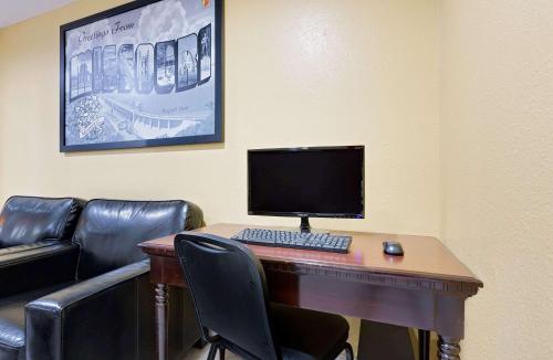 a desk with a computer monitor and a keyboard at Super 8 by Wyndham Rock Port MO in Rock Port