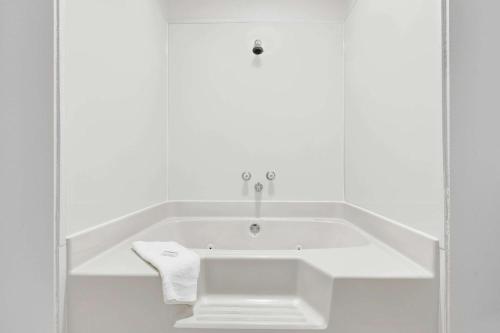 a white bath tub in a white bathroom with a towel at Super 8 by Wyndham Rock Port MO in Rock Port