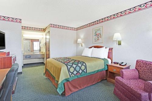 um quarto de hotel com uma cama e uma cadeira em Super 8 by Wyndham Tucson Downtown Convention Center em Tucson