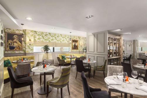 a restaurant with tables and chairs and a bar at Ramada Hotel & Suites by Wyndham Coventry in Coventry
