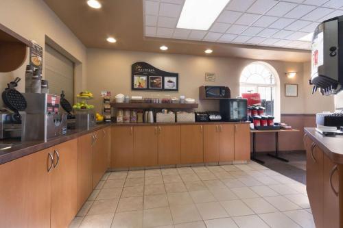 a kitchen with wooden cabinets and a counter in a restaurant at Days Inn & Suites by Wyndham Thunder Bay in Thunder Bay