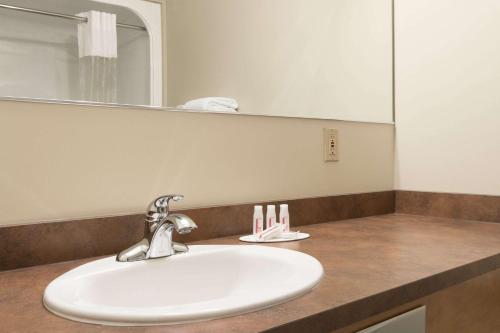 a bathroom counter with a sink and a mirror at Days Inn & Suites by Wyndham Thunder Bay in Thunder Bay
