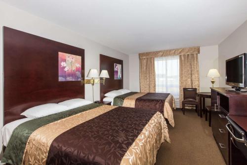 a hotel room with two beds and a flat screen tv at Super 8 by Wyndham Innisfail in Innisfail
