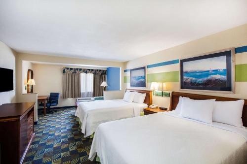 Habitación de hotel con 2 camas y TV de pantalla plana. en Days Inn & Suites by Wyndham Corpus Christi Central, en Corpus Christi
