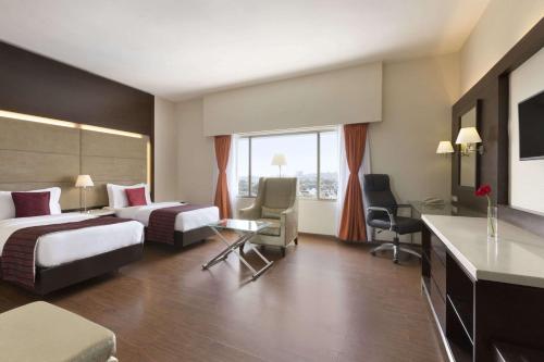 a hotel room with two beds and a desk at Ramada by Wyndham Chennai Egmore in Chennai