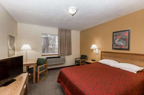 um quarto de hotel com uma cama, uma secretária e uma televisão em Days Inn by Wyndham Atlantic em Atlantic