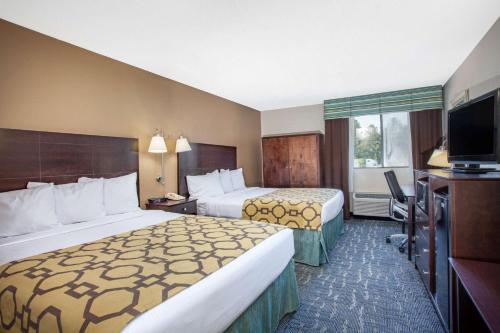 a hotel room with two beds and a flat screen tv at Baymont by Wyndham Saraland in Saraland