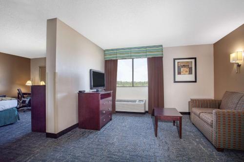 a hotel room with a couch and a television at Baymont by Wyndham Saraland in Saraland