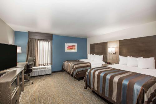 a hotel room with two beds and a flat screen tv at Wingate by Wyndham Louisville Airport Expo Center in Louisville