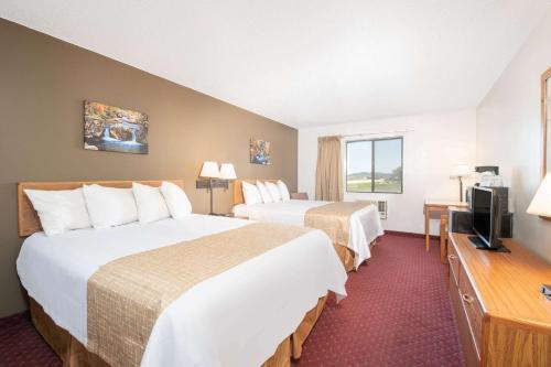 a hotel room with two beds and a television at Travelodge by Wyndham Spearfish in Spearfish