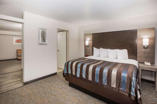 a hotel room with a large bed and a bathroom at Wingate by Wyndham Louisville Airport Expo Center in Louisville