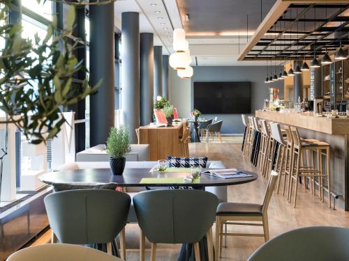 a restaurant with a table and chairs and a bar at Novotel München City in Munich