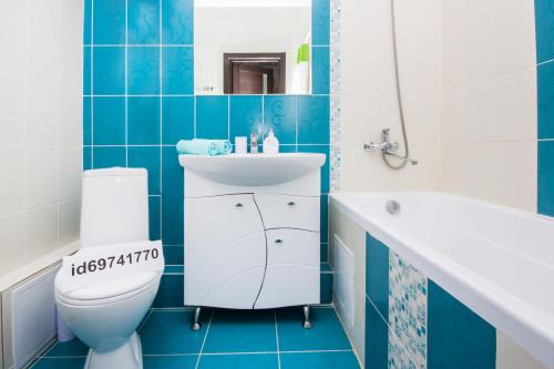 a blue tiled bathroom with a toilet and a sink at Apartments of PANORAMA Krasnodar in Krasnodar