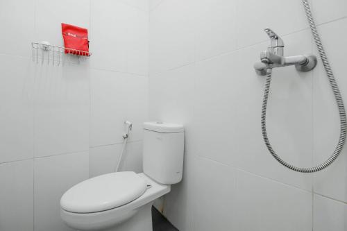 a white bathroom with a toilet and a shower at RedDoorz near Siloam Hospital Palembang in Palembang