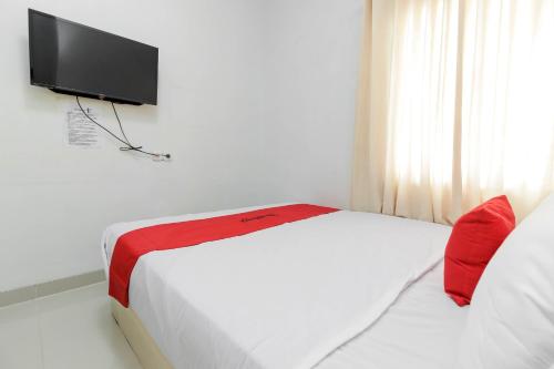 a bedroom with a bed with a television on the wall at RedDoorz near Siloam Hospital Palembang in Palembang