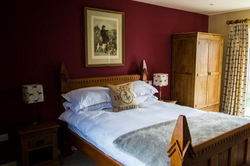 a bedroom with a large bed with red walls at The Three Chimneys Country Pub in Biddenden