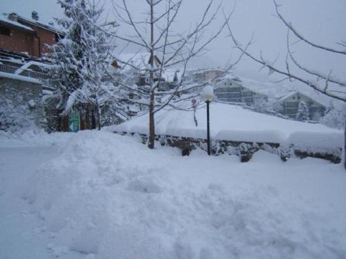 a yard covered in snow with a tree and buildings at Hotel Ristorante Miravalle in Teglio