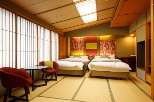 a hotel room with two beds and a table and chairs at Tamatsukuri Grand Hotel Choseikaku in Matsue