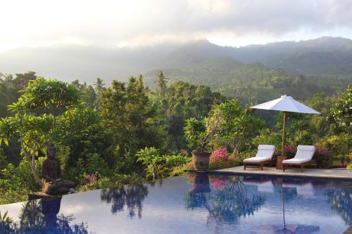 a swimming pool with two chairs and an umbrella at Shanti Natural Panorama View Hotel in Singaraja