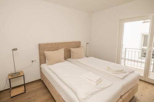 a white bedroom with a large bed with white sheets at MeerBlickD21 Residenzen in Norderney