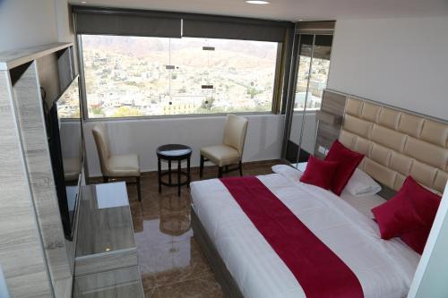 a bedroom with a bed and a large window at Petra Sella Hotel in Wadi Musa