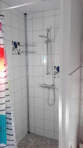 La salle de bains est pourvue d'une douche et de murs carrelés blancs. dans l'établissement 10 bis, à Lagorce