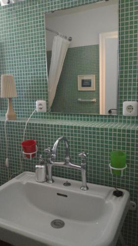 ein grün gefliestes Badezimmer mit Waschbecken und Spiegel in der Unterkunft Aisching in Gstadt am Chiemsee