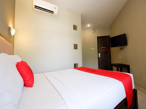 a bedroom with a white bed with red pillows at RedDoorz Plus @ Singosari Raya in Semarang