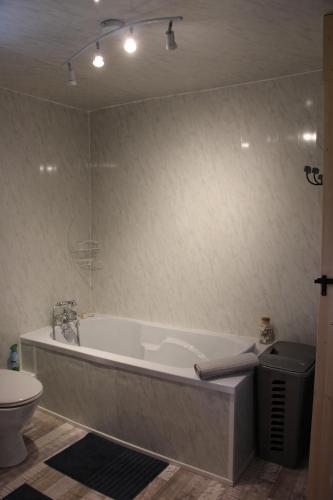 La salle de bains est pourvue d'une baignoire blanche et de toilettes. dans l'établissement Cute Gite family Aucey Mont Saint Michel, à Aucey-la-Plaine