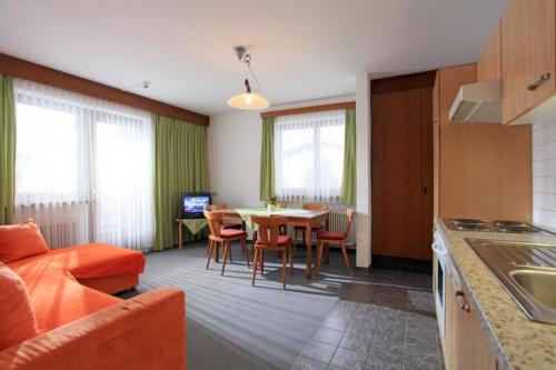 een keuken en een woonkamer met een tafel en stoelen bij Pension Mannharthof in Westendorf