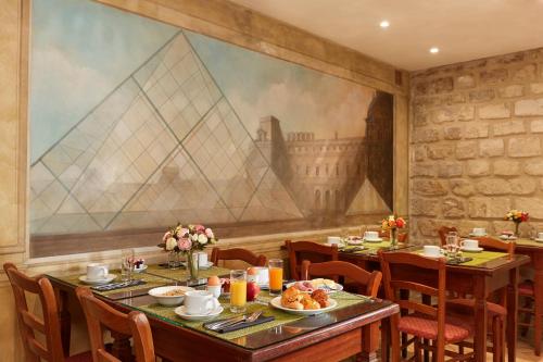 une salle à manger avec des tables et des chaises et un grand tableau dans l'établissement Montparnasse Daguerre, à Paris