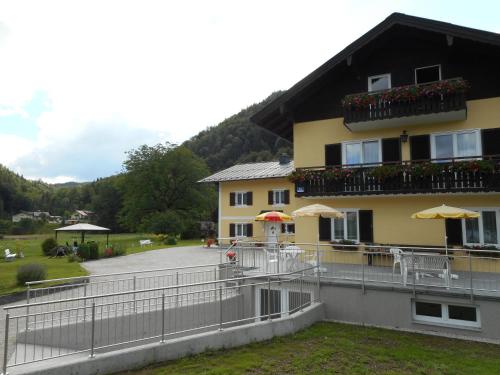 a yellow house with a balcony and tables and umbrellas at Haus Amalia in Strobl