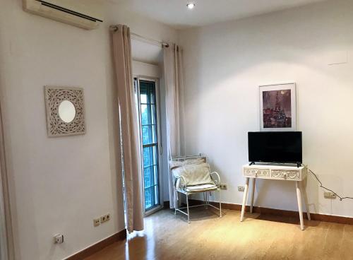 a living room with a television and a table with a chair at Triana Luxury Home in Seville