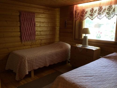 Habitación con 2 camas y ventana en una habitación en Rissalan Lomamökit en Juankoski