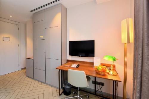 a room with a desk with a television and a chair at Upsuites Hotel in Istanbul