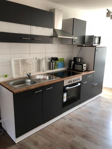 a kitchen with black and white cabinets and a sink at Apartments Stadtmauer in Northeim