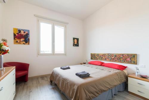 een witte slaapkamer met een bed en een rode stoel bij Visarno Arena Apartment in Florence