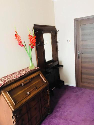 a vase of flowers on top of a dresser with a mirror at Willa Sorrento in Szczecin