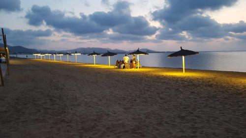 ラ・マンガ・デル・マール・メノールにあるDúplex Completo La Manga dos playasの浜辺の傘下に座る人々