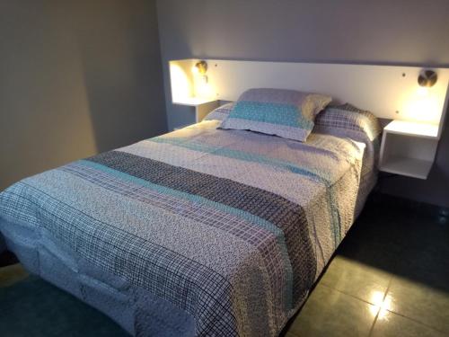 um quarto com uma cama com um cobertor listrado em Los Nietos hospedaje em Mendoza