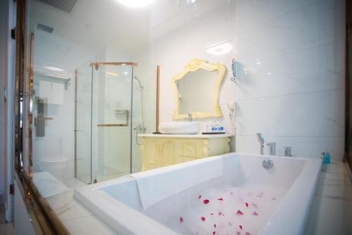 a bathroom with a tub with a shower and a sink at Canh Hung Palace in Hai Phong