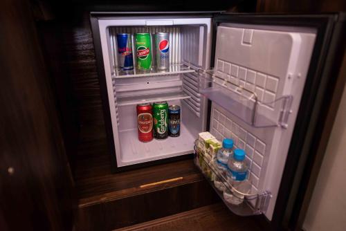 an open refrigerator filled with drinks and sodas at White Ridge Hotel in Dharamshala