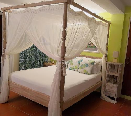a bedroom with a canopy bed and a window at Villa Touloulou in English Harbour Town