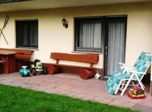 ein Haus mit einer Bank, einem Stuhl und einem Spielzeugauto in der Unterkunft Ferienwohnungen Zeltnerhof in Breitenbrunn