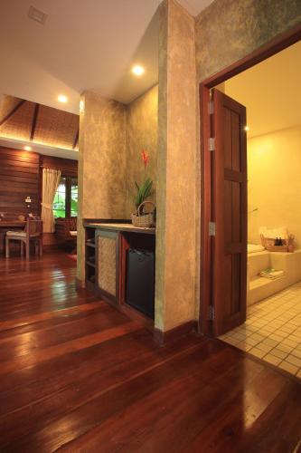 a living room with a wooden floor and a door at Azalea Village in Chiang Dao