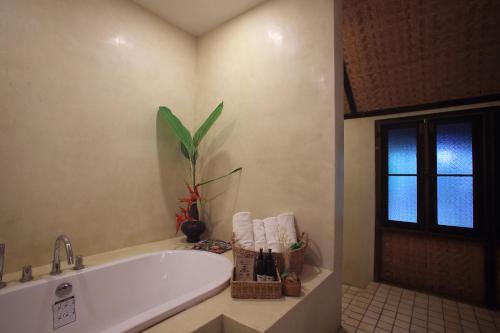 a bathroom with a tub and a plant next to a window at Azalea Village in Chiang Dao