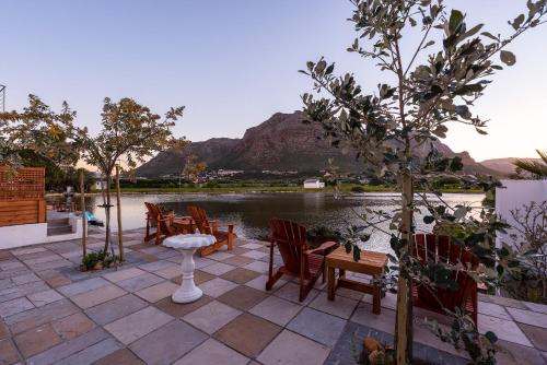 a patio with chairs and a table with a mountain in the background at Marina Views in Muizenberg