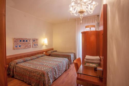 Habitación de hotel con 2 camas, mesa y lámpara de araña. en Hotel Terme Orvieto, en Abano Terme
