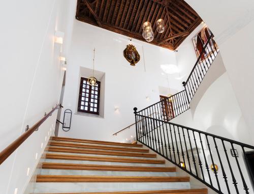 a staircase in a house with white walls and wooden ceilings at One Shot Conde Torrejón in Seville